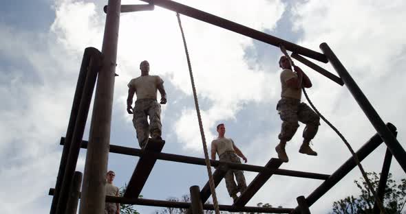 Military troops climbing rope during obstacle course alt