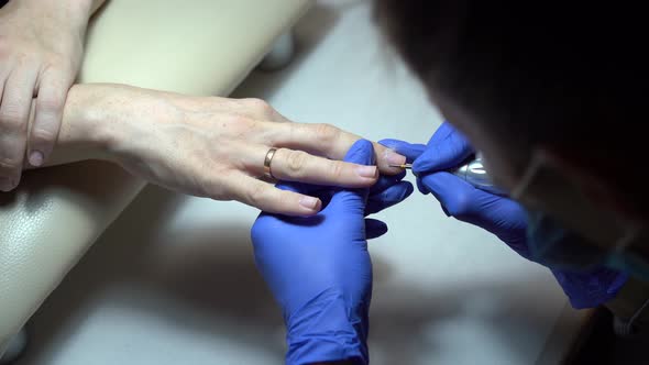 Manicure procedure in salon with electric nail drill machine.