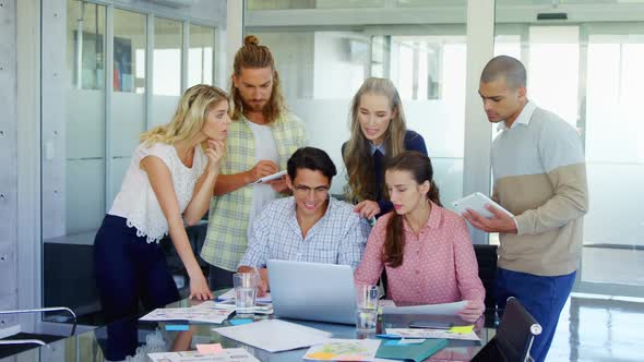 Colleagues discussing over laptop at table 4k alt