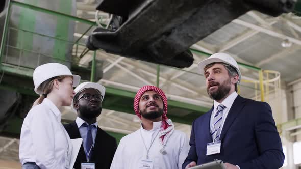 Multi-ethnic business people looking at mechanism at factory