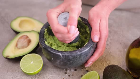 Making Guacamole Sauce  Woman Mashing Avocado in a Marble Mortar with Pestle at Domestic Kitchen alt