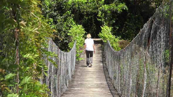 Woman Walking on the Hanging Suspension Bridge alt