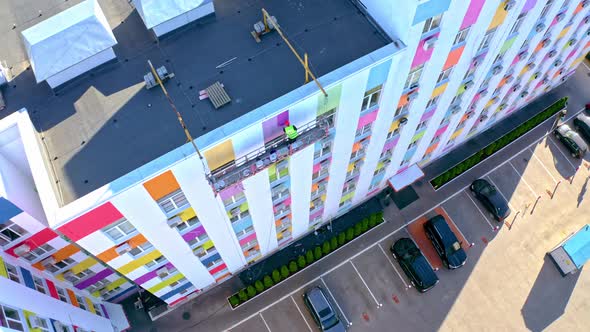 A Worker Paints The Facade Of A Building At A Height.