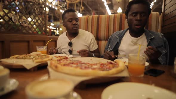 Two African American Guys Eat Funny Pizza in a Restaurant