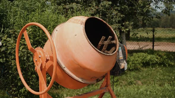 New Orange Concrete Mixer on the Territory of the Cottage Small Portable Machine for Mixing Cement
