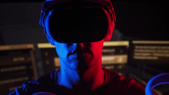 Man in a Virtual Reality Helmet Illuminated in Red and Blue Plays a Game alt