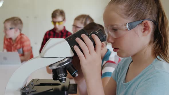 Girl wearing glasses using microscope alt