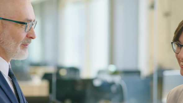 Senior Businessman Speaking with Young Female Colleague alt