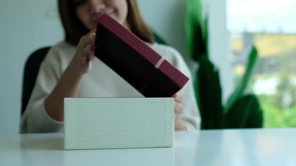 Closeup of a young woman opening a red present box