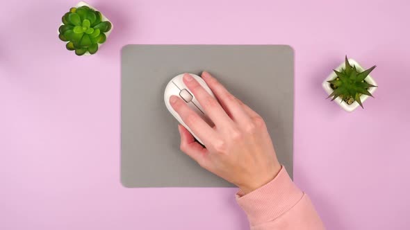 A female hand controls a white computer mouse