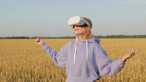 Beautiful Girl in a Golden Wheat Field Uses Virtual Reality Glasses