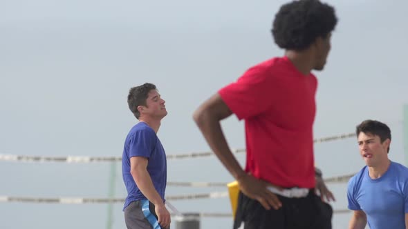 A group of guys playing flag football on the beach. alt