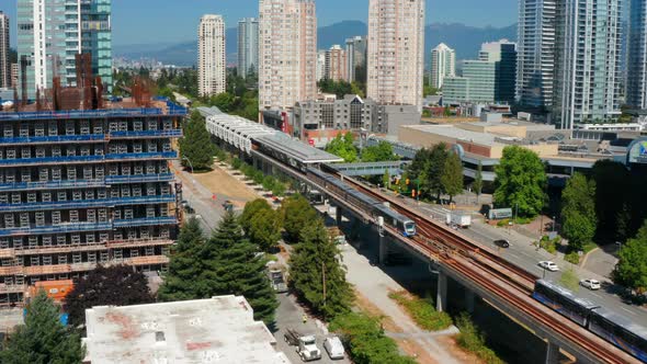 SkyTrain Departing From Metrotown Station In Burnaby, British Columbia, Canada. aerial ascend alt