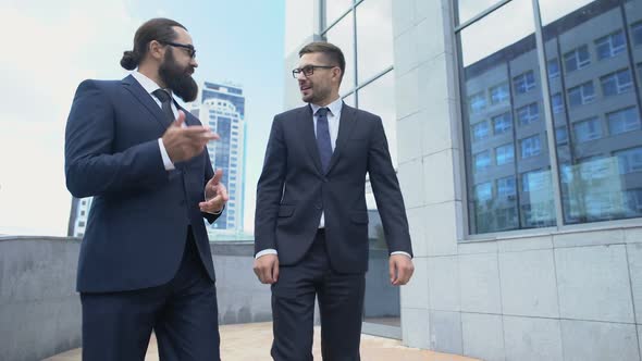 Two Business Men Walking Street and Actively Discussing Contract Conditions