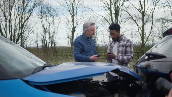 Senior and younger male drivers at side of the road exchanging car insurance details
