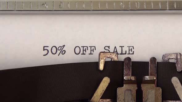 Typing phrase 50% OFF SALE on retro typewriter. Close up. alt