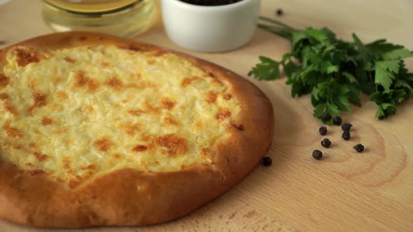Round Cake with Cheese Rotates on Wooden Tray with Olive Oil Parsley