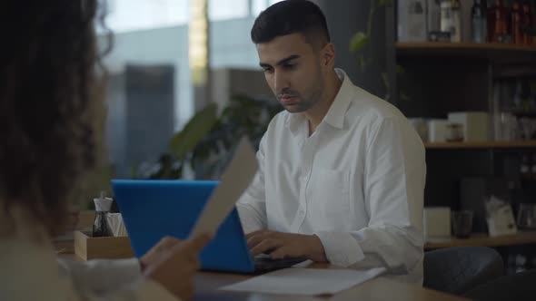 Portrait of Confident Middle Eastern Businessman Using Laptop and Talking with Unrecognizable alt
