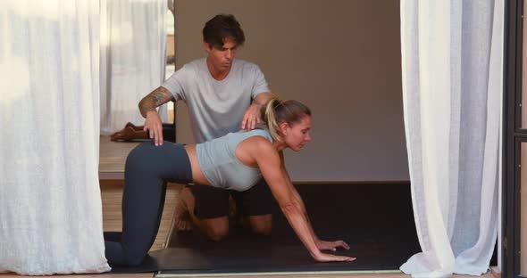 Trainer supporting woman doing plank exercise alt