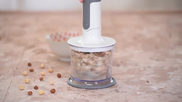 A Woman Chopping Almonds And Hazelnuts In A Food Processor