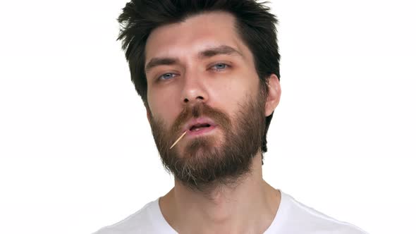 Young Bearded Man with a Toothpick in Mouth Acting Loose on White Background alt