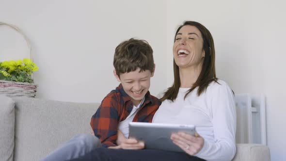 Mother and son having fun watching movie on digital tablet