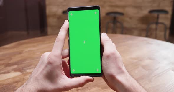 POV Shot of Male Hands Holding a Phone with Green Screen alt