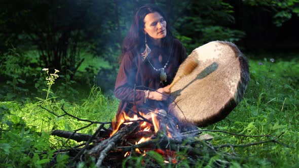 Shaman woman drumming in a trance in the forest