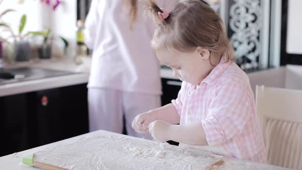 Little Girl Cooking with Caring Mother at Kitchen