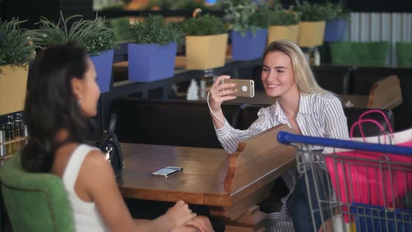 Young Woman Take Photo of Her Friend in Mall Using Smartphone alt