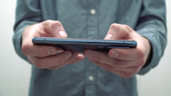 Businessman at home writing a message on a smartphone, holding it horizontally