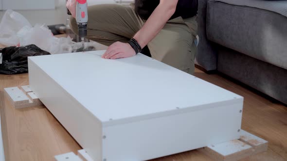 The Master Furniture Maker Drills a Hole in the Cabinet Body with a Screwdriver for Fastening with a alt