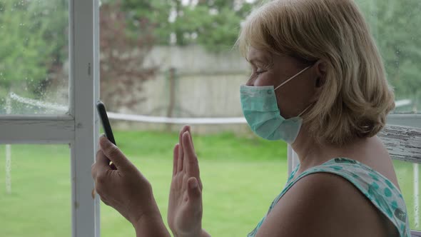 Woman In Self Isolation Communicates With Her Family Via Video Link On Her Phone alt