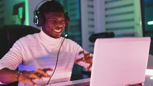 Disappointed Young Black Man with Illuminated Headset Using Laptop. Home Office and Remote Work alt