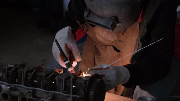 Professional men wearing welding mask and gloves work in home workshop with arc welding and argon. alt