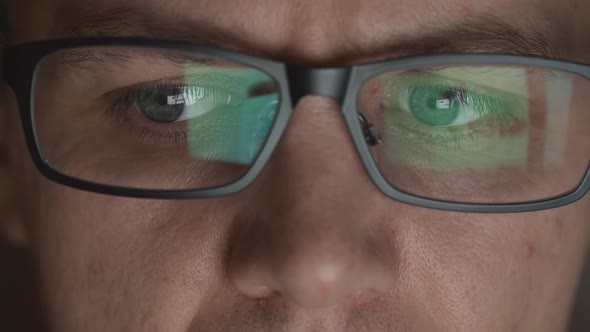 Reflection Of Scrolling Sites In An Eyeglasses Of Young Adult Man In A Dark Room