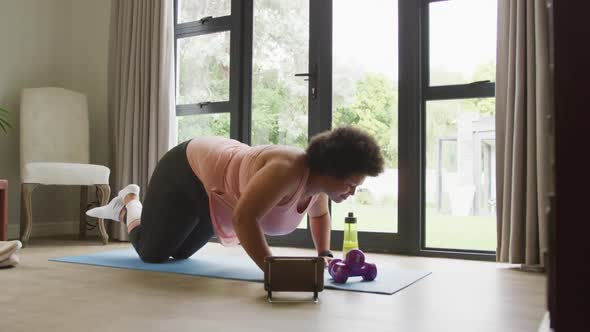 Video of midsection of plus size african american woman exercising with online lessons at home alt