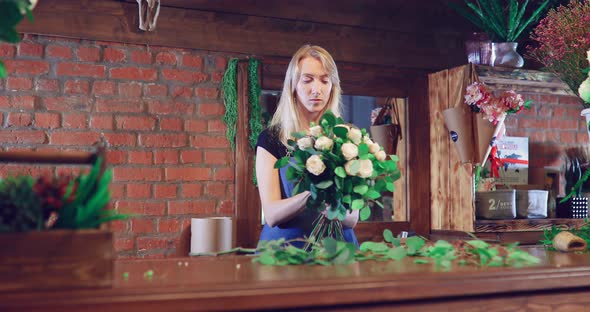 Florist Packs a Rose  Girl Composes Flowers in a Bouquet  Flower Shop alt