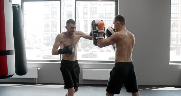 MMA Fighter is Practising His Strikes with Trainer in Slow Motion in the Gym Kickboxers are Training alt