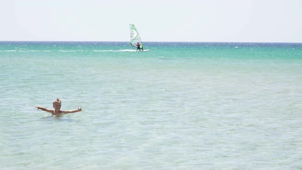 Happy Child Swims in the Sea Near the Shore and Learns To Swim alt