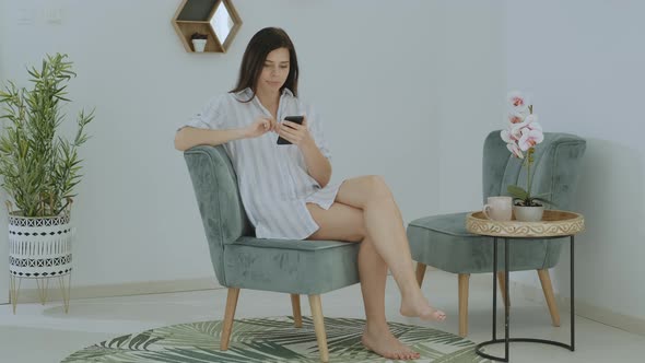 Attractive brunette woman  in casual clothes typing message on phone at home office alt