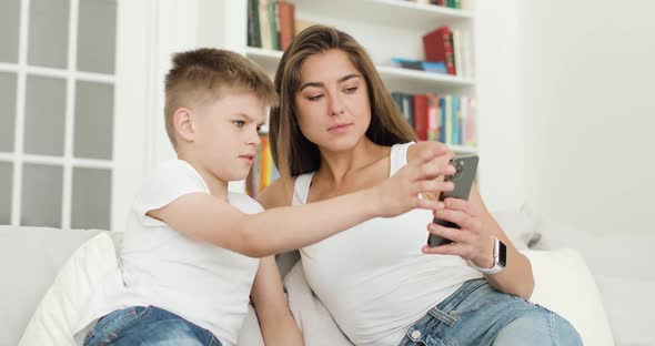 Mother and Son Looking at Smartphone Screen Browsing Internet Doing Shopping Online alt