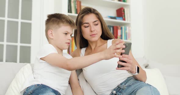 Mother and Son Looking at Smartphone Screen Browsing Internet Doing Shopping Online