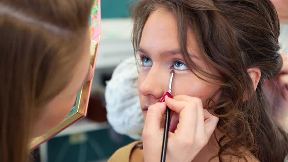 The Girl Master with a Brush Applies Shadow to the Eyelid Closeup alt