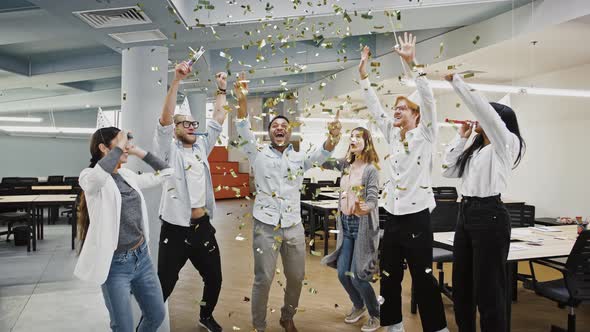 Group of Diverse Colleagues in Party Hats are Blowing in Whistles Smiling and Dancing Celebrating alt