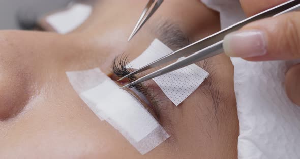 Female having eye lash extension in beauty salon alt