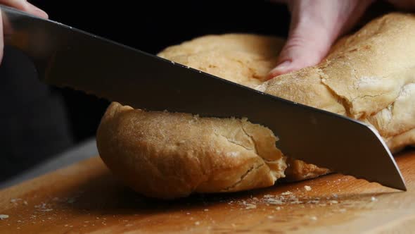 A Woman Cutting a Loaf of Bread with a Bread Knife. Slow Motion