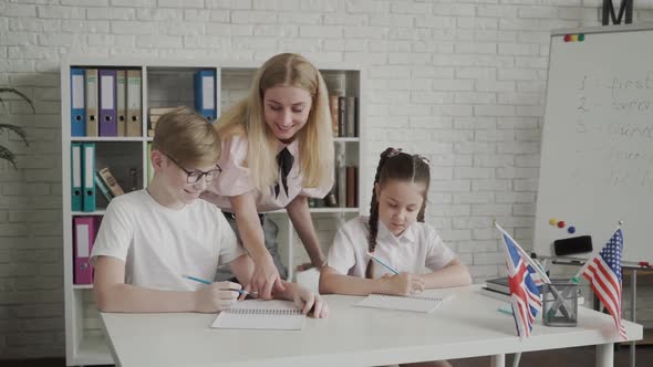 Young Teacher Helping Pupil Learning and Explaining Mistakes alt