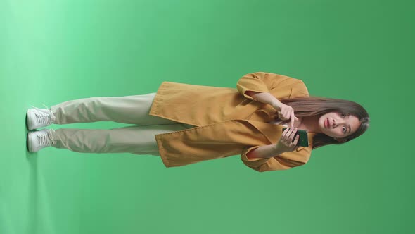 Full Body Of Young Asian Woman Use Phone Becoming Surprised And Saying Wow In Green Screen Studio alt