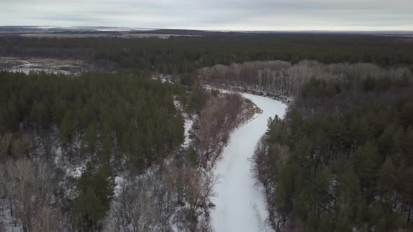 Landscape with Frozen Riverbed in Forest in Winter Day, Aerial Shot